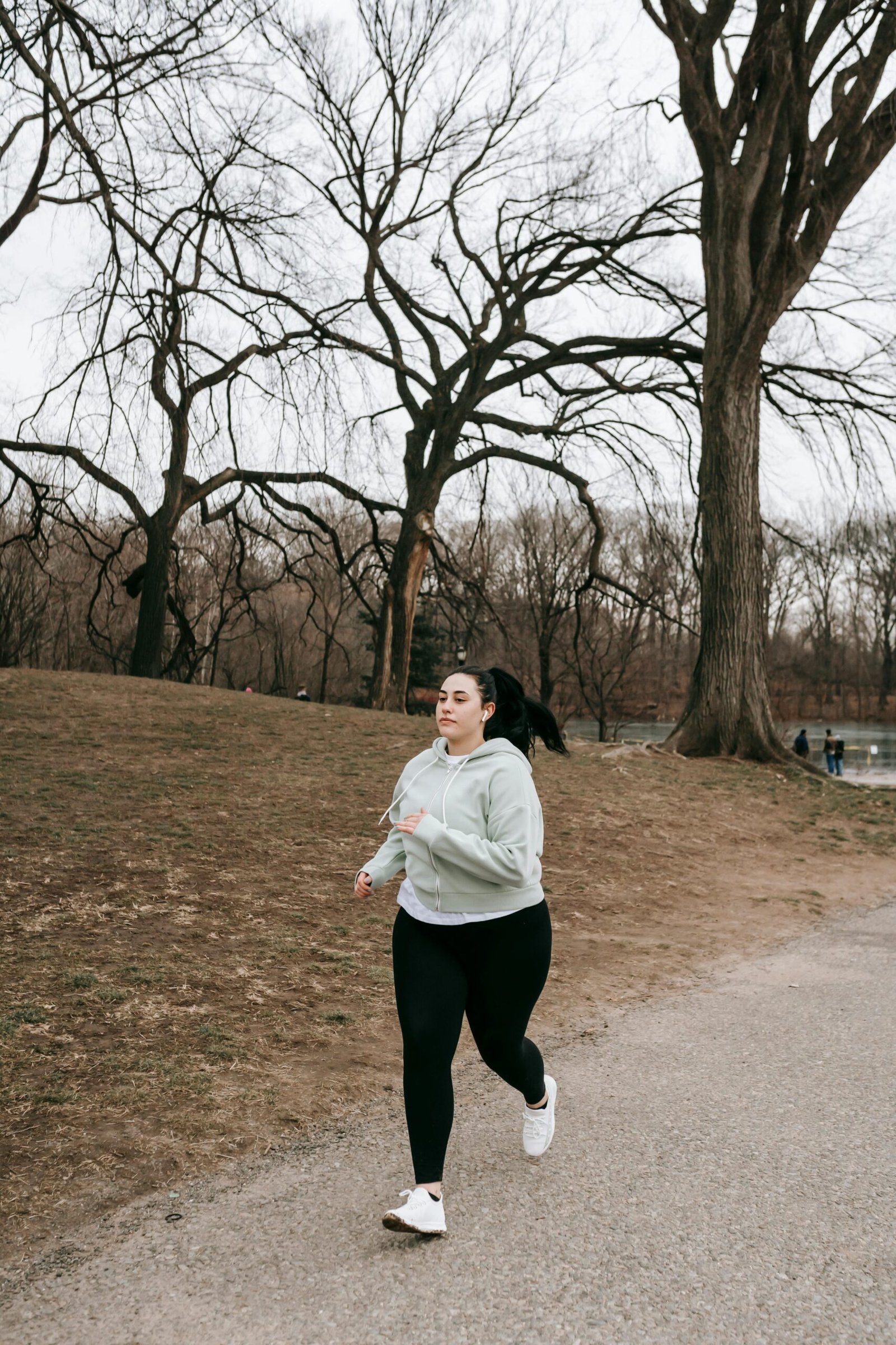 a woman in a gray hoodie running on a path